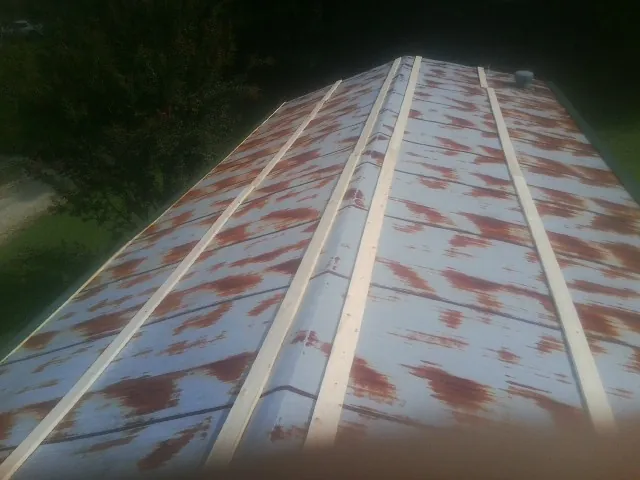 Rusted metal roof panels with new wood purlins before replacement in Russellville