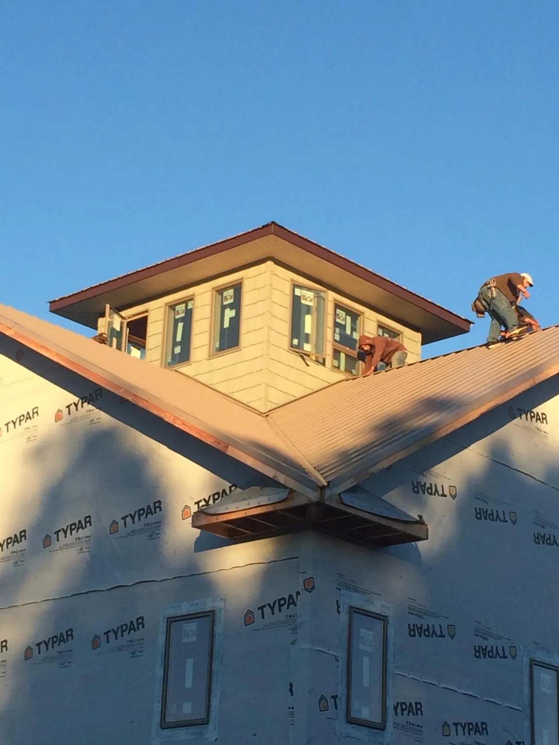Roofers working around a rooftop cupola on a new metal roof at sunset — Roof Waterproofing in Russellville by Roofing Brothers